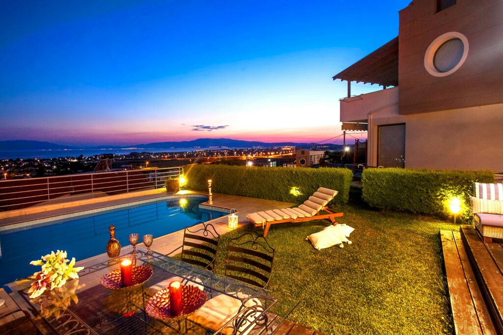 Modern backyard with elegant outdoor dining setup, lounge chair, and a rectangular pool overlooking the city—highlighting 2025 swimming pool trends.