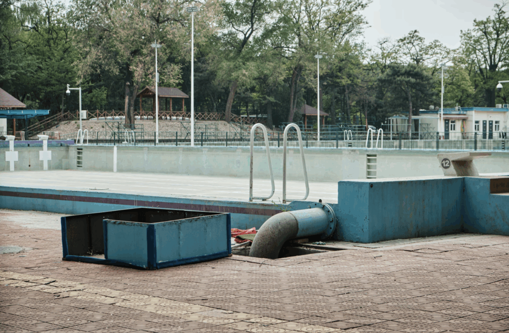 An abandoned outdoor swimming facility featuring a large empty pool, showing why many owners ask how long do pool pumps usually last when systems fail.